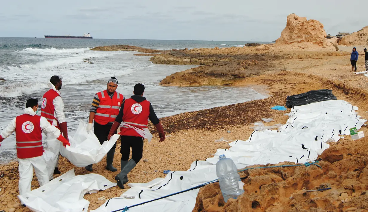Petugas Bulan Sabit Merah Libya mengevakuasi jenazah para migran yang ditemukan terdampar di pantai utara Libya, Selasa (21/2). Sedikitnya 74 jenazah imigran tenggelam saat melintasi perairan Mediterania dalam upaya mencapai Eropa. (MOHANED KREMA/AFP)