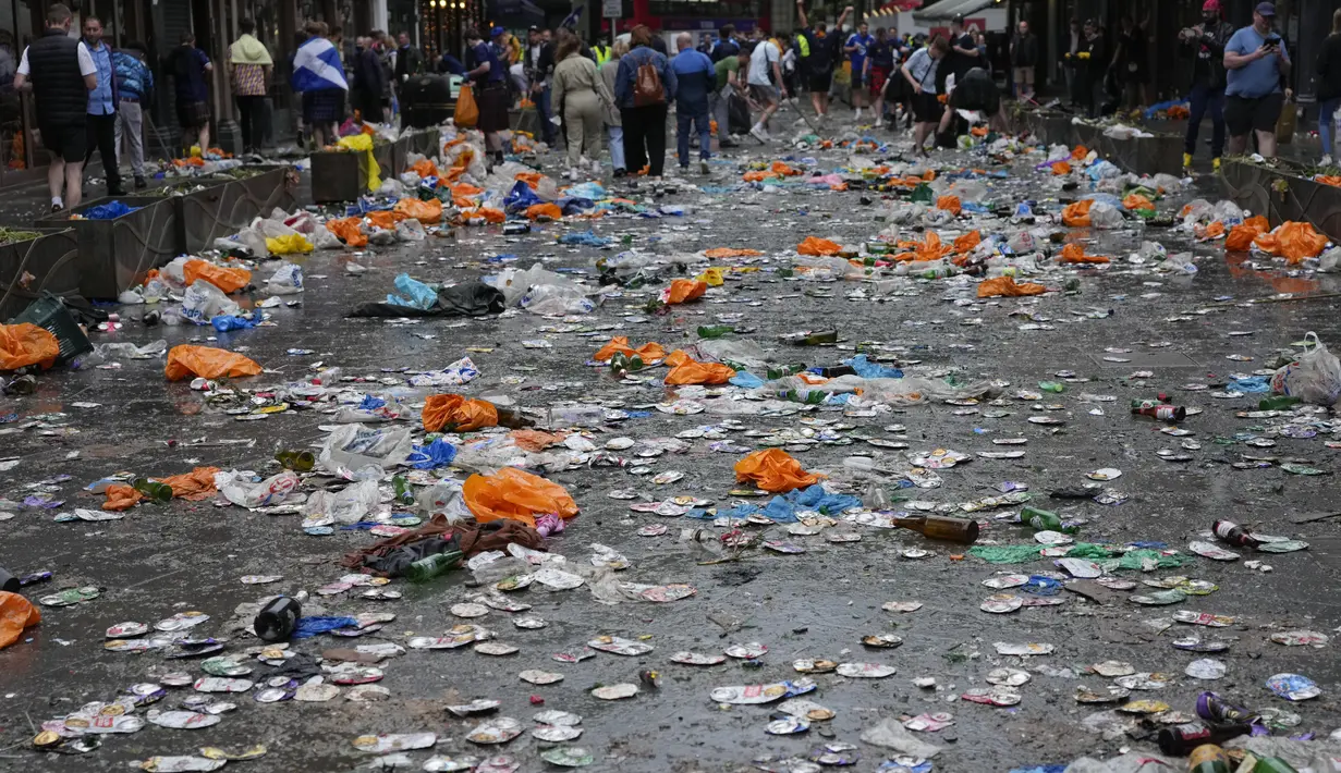 Suporter Skotlandia membantu membersihkan sampah yang ditinggalkan fans yang berpesta jelang pertandingan grup D Euro 2020 melawan Inggris di London, Jumat (18/6/2021). (AP Photo/Kirsty Wigglesworth)