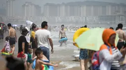 Orang-orang mengunjungi pantai sambil mendinginkan diri di Qingdao, China timur, pada 3 Agustus 2019. Banyak warga di Negeri Tirai Bambu memanfaatkan musim panas dengan mengunjungi pantai untuk mengisi liburan. (Photo by FRED DUFOUR / AFP)