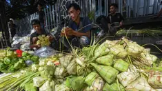 Pedagang melayani pembuatan kulit ketupat di Pasar Pondok Labu, Jakarta Selatan, Minggu (30/3/2025). (merdeka.com/Arie Basuki)