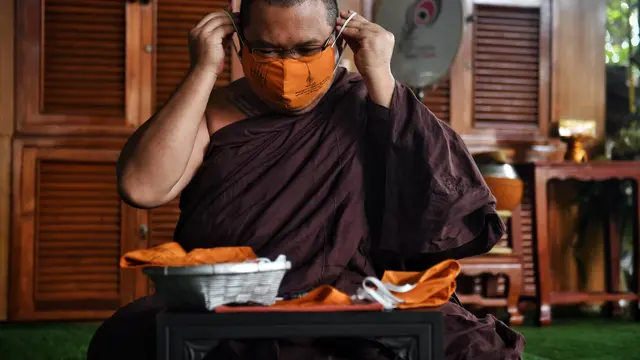 Biksu Budddha Chamnanwej Sutthiyano mengenakan masker terbuat dari botol plastik daur ulang dan ditulisi mantra spiritual, (Lillian Suwanrumpha/AFP)