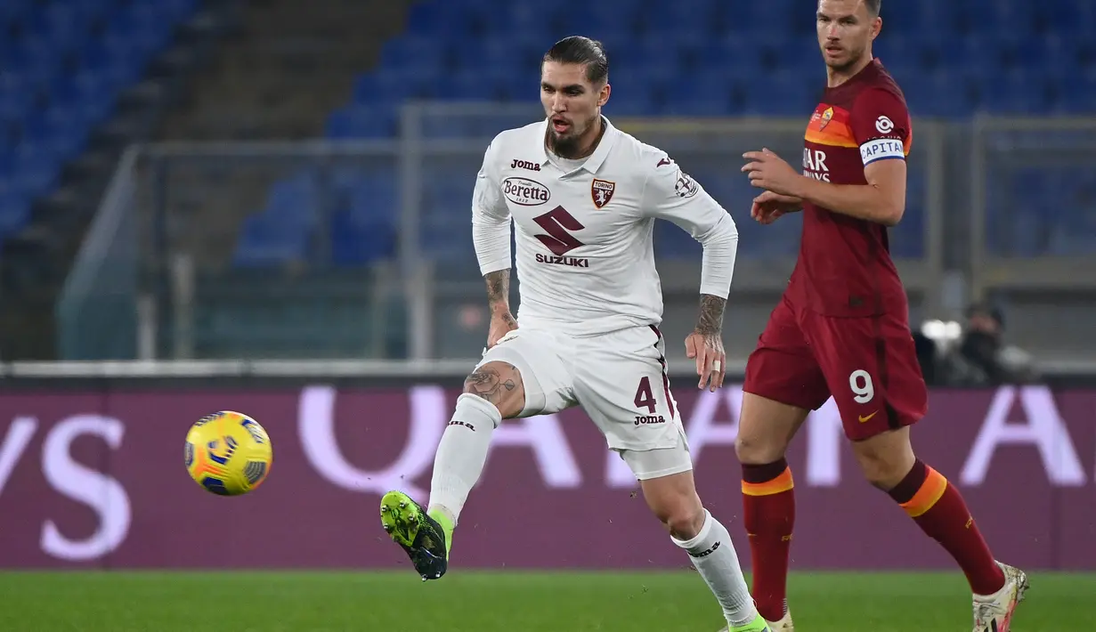 Bek Torino Lyanco Vojnovic mengoper bola dari kawalan penyerang Roma Edin Dzeko pada pertandingan Liga Serie A Italia di stadion Olimpiade, Jumat (18/12/2020). Berkat kemenangan itu, Roma kini melejit ke posisi ke-4 klasemen sementara Liga Italia. (AFP Photo/Vincenzo Pinto)