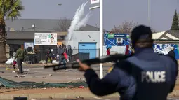 Orang-orang melempari polisi dengan batu ketika mereka mencoba menjarah di Pusat Perbelanjaan Letsoho di Katlehong, sebelah timur Johannesburg, Senin (12/7/2021). Kerusuhan dan penjarahan yang dipicu penahanan mantan Presiden Afrika Selatan Jacob Zuma. (AP/Themba Hadebe)