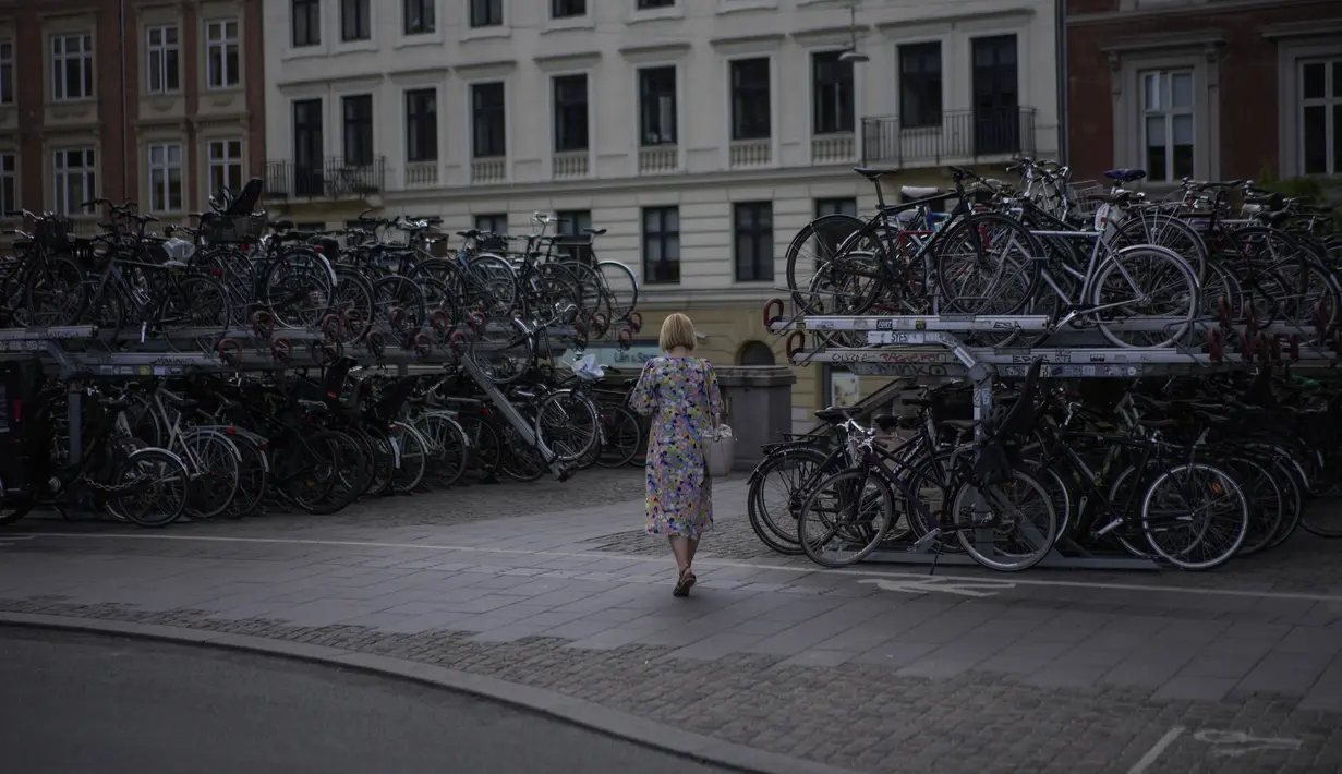 Seorang perempuan berjalan di tempat parkir sepeda di Kopenhagen, Denmark, Selasa (28/6/2022), saat negara itu bersiap untuk menjadi tuan rumah tiga tahap pertama dari Tour de France Cycling Race mulai 1 Juli mendatang. (AP Photo/Thibault Camus)