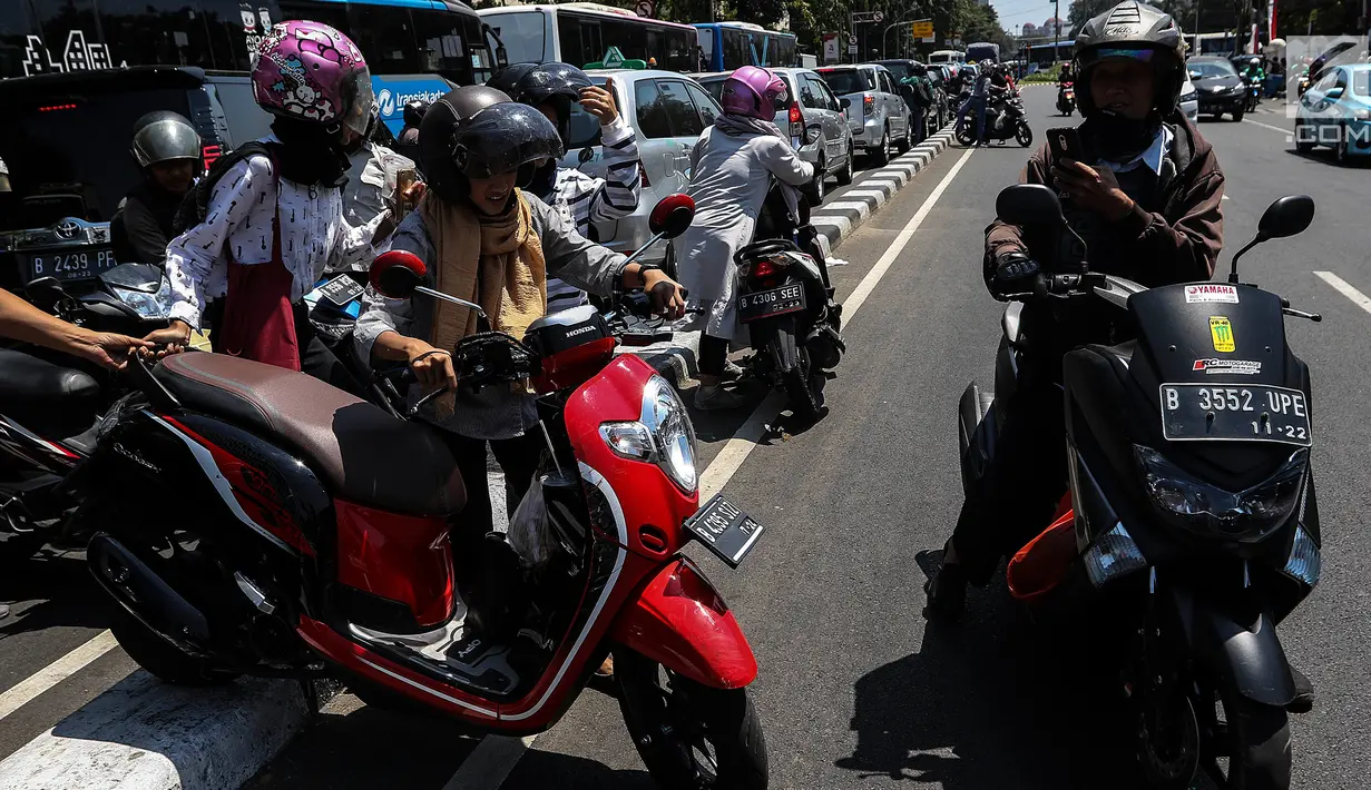 Pengendara berusaha pindah jalur dengan mengangkat sepeda motor mereka melewati pembatas jalan di kawasan Ridwan Rais, Jakarta, Rabu (21/8/2019). Pengendara motor tersebut berpindah jalur disebabkan tidak sabar menunggu kemacetan. (Liputan6.com/Johan Tallo)