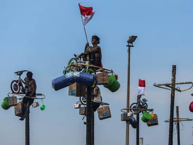 Peserta mengikuti perlombaan panjat pinang di pantai Ancol, Jakarta, Sabtu (17/8/2024). (Liputan6.com/Angga Yuniar)