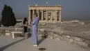 Pengunjung berdiri dekat Kuil Parthenon di Bukit Acropolis, Athena, Yunani, Senin (18/5/2020). Yunani kembali membuka kota kuno Acropolis serta situs-situs lainnya setelah dua bulan ditutup selama lockdown akibat pandemi virus corona COVID-19. (AP Photo/Petros Giannakouris)