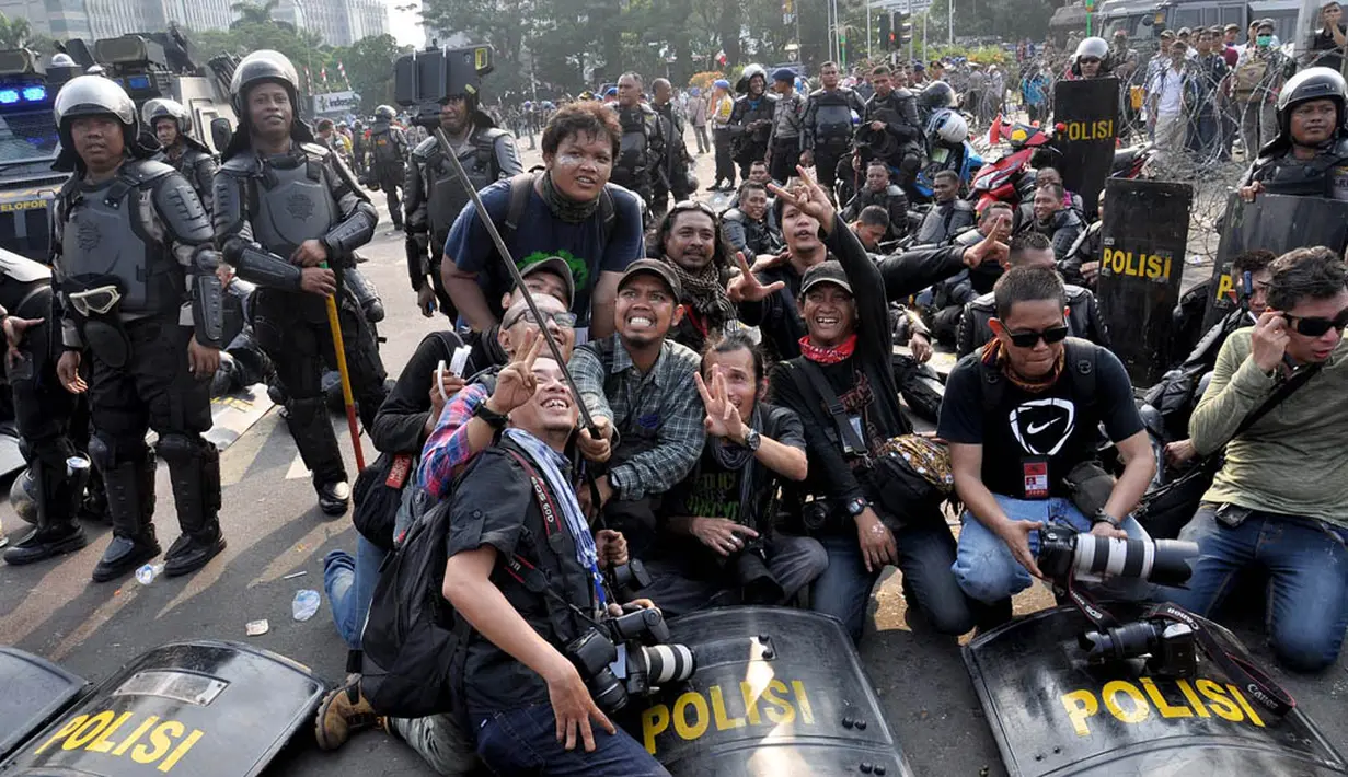Sejumlah pewarta foto sibuk ber-selfie ria dengan latar belakang petugas Kepolisan, Jakarta, Kamis (21/8/14).(Liputan6.com/Miftahul Hayat)