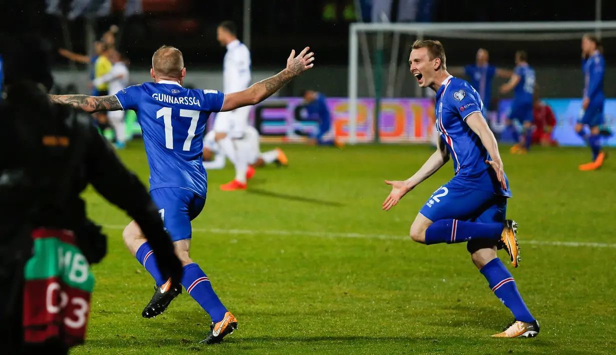 Pemain Islandia, Aron Einar Gunnarsson dan Jon Dadi Bodvarsson merayakan kemenangan atas Kosovo saat Grup I Kualifikasi Piala Dunia 2018 di Laugardalsvollur, Senin (9/10). Menang 2-0, Islandia pertama kalinya tampil di Piala Dunia. (AP/Brynjar Gunnarsson)