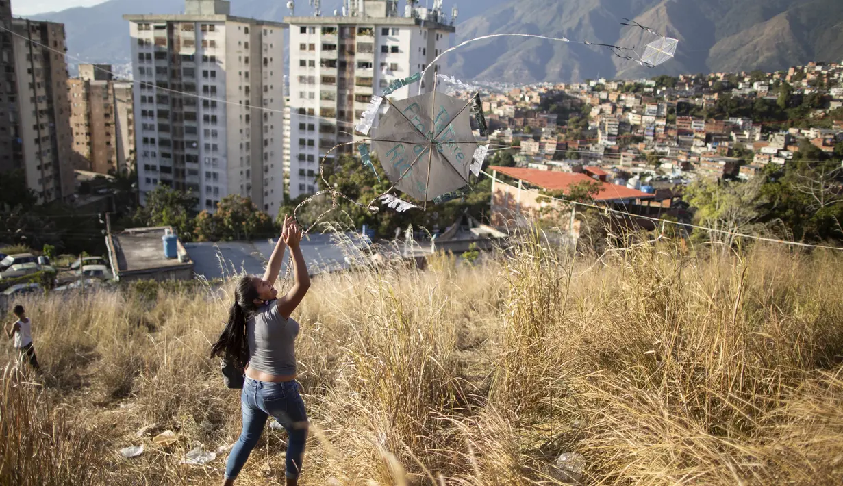 Seorang wanita muda menerbangkan layang-layang dalam acara peringatan 400 tahun permukiman kumuh Petare di Caracas, Venezuela (17/2/2021). Petare yang merupakan kawasan kumuh terbesar di Venezuela menjadi rumah bagi lebih dari 500.000 jiwa. (AP Photo/Ariana Cubillos)