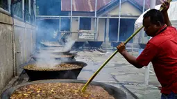 Seorang pria memasak kari tradisional untuk disajikan dalam makanan komunal selama bulan suci Ramadhan di Banda Aceh (25/4/2021). Biasanya, kari tradisional ini juga akan dibagi-bagikan kepada fakir, miskin dan anak yatim. (AFP/Chaideer Mahyuddin)