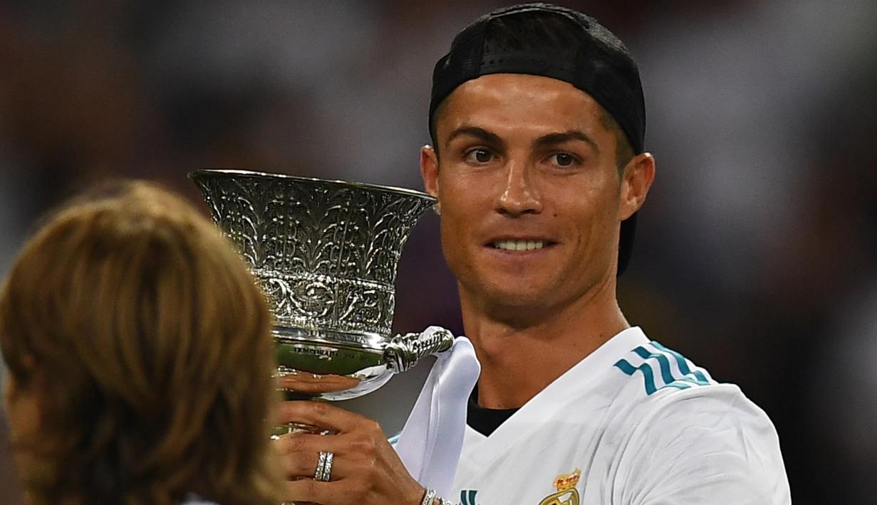 Senyum Cristiano Ronaldo saat memegang trofi Piala Super Spanyol 2017 di di Santiago Bernabeu stadium, Madrid, (16/8/2017). Real menang agregat 5-1. (AFP/Gabriel Bouys)