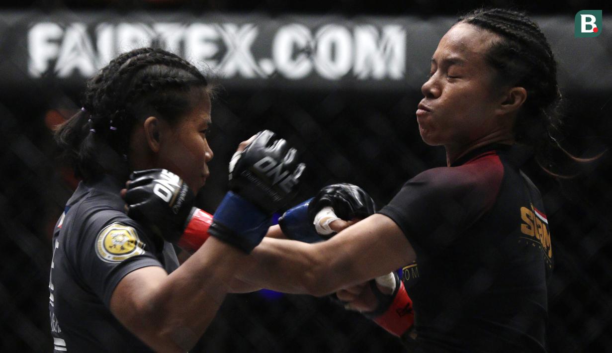 Petarung Indonesia, Priscilla Lumban Gaol, beradu pukulan dengan petarung Filipina, Angelie Sabanal, pada laga One Championship di Istora Senayan, Jakarta, Sabtu (17/11). Priscilla meraih kemenangan angka di kelas atomweight. (Bola.com/Yoppy Renato)