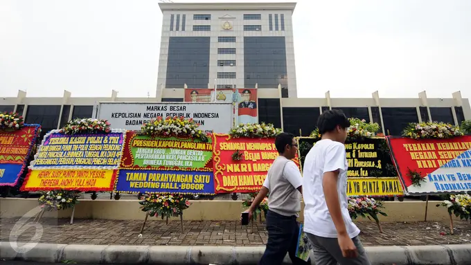 Warga melintasi deretan karangan bunga yang diletakkan di depan Mabes Polri, Jakarta, Rabu (3/5). Ratusan karangan bunga itu terus berdatangan dan mengelilingi gedung Mabes Polri di Jalan Trunojoyo Jakarta Selatan. (Liputan6.com/Helmi Fithriansyah)