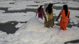 Sejumlah wanita mandi di sungai Yamuna yang tertutup busa limbah sebagai bagian dari ritual untuk festival Chhath Puja yang akan datang di New Delhi, Senin (8/11/2021). Sungai yang sangat dianggap suci oleh umat Hindu India ini dipenuhi lapisan busa karena limbah beracun. (Sajjad HUSSAIN / AFP)