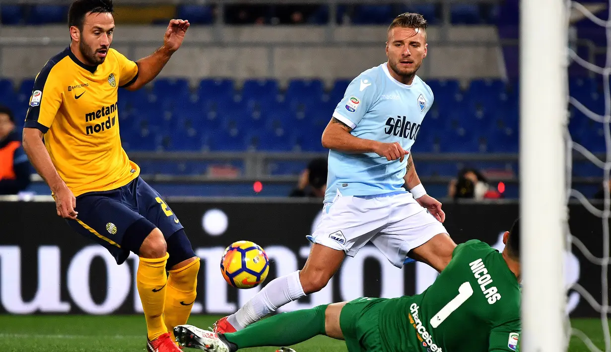 Aksi pemain Lazio, Ciro Immobile (tengah) berebut bola dengan bek Hellas Verona, Martin Caceres (kiri) dan kiper Nicolas Andrade pada lanjutan Serie A di di Olympic stadium, Roma, (19/2/2018). Lazio menang 2-0. (AFP/Alberto Pizzoli)