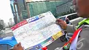 Seorang Petugas membentangkan peta jalur mudik yang dibagikan secara gratis kepada para pengguna jalan, Jakarta, Jumat (18/07/2014)(Liputan6.com/Faizal Fanani)