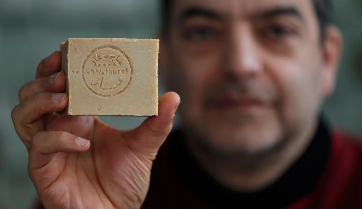 Pengusaha sabun zaitun khas Aleppo menunjukkan sabun yang telah berubah warna usai menjalani proses pengeringan, Paris, Kamis (22/12). Kota Aleppo yang tak lagi aman membuat pengusaha sabun ini pindah ke Paris. (REUTERS / Christian Hartmann)
