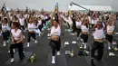 Para penggemar yoga melakukan yoga selama acara "Brew Yoga" saat matahari terbit di landasan pacu Bandara Suvarnabhumi di Bangkok, Thailand, Sabtu (27/4/2024). (MANAN VATSYAYANA / AFP)