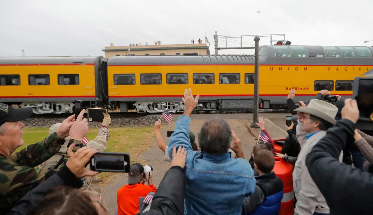 Warga memberi hormat saat kereta pembawa peti jenazah Presiden ke-41 AS George HW Bush melintasi Navasota, Texas, Kamis (6/12). Kereta pembawa jenazah presiden ke-41 AS itu ditarik oleh lokomotif yang didesain khusus. (AP Photo/Gerald Herbert)