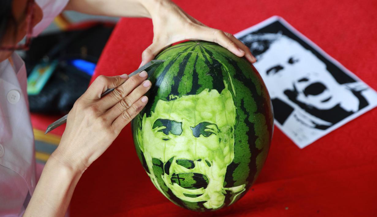 Seorang siswa sekolah menengah mengukir wajah pemain sepak bola Polandia, Robert Lewandowski pada buah semangka di Shenyang, Provinsi Liaoning, China, Senin (9/7). (AFP)