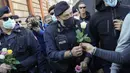 Petugas polisi menerima bunga yang diberikan demonstran selama aksi protes di Circus Maximus Roma, Jumat (15/10/2021). Protes tersebut karena aturan yang mengharuskan seluruh pekerja di Italia menunjukkan kartu kesehatan covid-19 untuk memasuki tempat kerja mereka. (AP Photo/Gregorio Borgia)