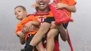 Bek Persija, Jaimerson Da Silva Xavier menggendong anak anaknya saat merayakan gelar juara Go-Jek Liga 1 Indonesia 2018 bersama Bukalapak di Stadion GBK, Jakarta, Minggu (9/12). Persija meraih juara dengan 62 poin. (Liputan6.com/Helmi Fithriansyah)