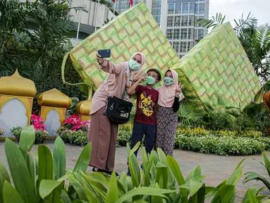 Sejumlah warga berfoto dengan dekorasi bertemakan Idul Fitri di kawasan Bundaran HI, Jakarta, Rabu (27/4/2022). Dekorasi berbentuk masjid, ketupat, dan bedug yang dihiasi oleh tanaman tersebut dalam rangka menyambut Idul Fitri 1443 Hijriah. (Liputan6.com/Faizal Fanani)