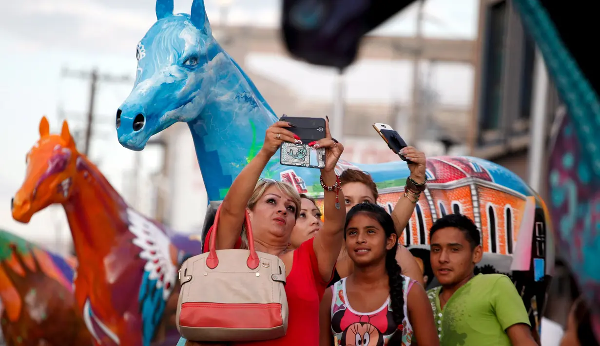  Sejumlah warga asik berselfie didepan patung kuda pusat kota Ciudad Juarez, Meksiko, Selasa (25/8/2015). 20 patung kuda dihias secara unik untuk menarik wisatawan. (REUTERS/Jose Luis Gonzalez)