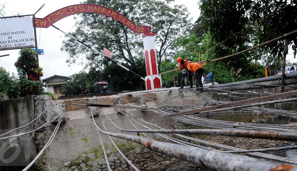 Petugas Suku Dinas Bina Marga Jakarta Barat memperbaiki Jembatan Kali Inspeksi Grogol, Jakarta, (30/5/2016). Pergeseran tanah di bawah Kali Irigasi Grogol sehingga pondasi jembatan bergeser dan permukaan jalan ambles. (Liputan6.com/Helmi Afandi)