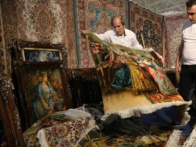 Pedagang memamerkan karpet tenun dagangannya kepada pengunjung pameran di Teheran, Iran, Kamis (29/8/2019). Eksportir karpet Iran kehilangan pasar AS setelah Presiden Donald Trump menjatuhkan sanksi berat terhadap negara tersebut. (AP Photo/Vahid Salemi)