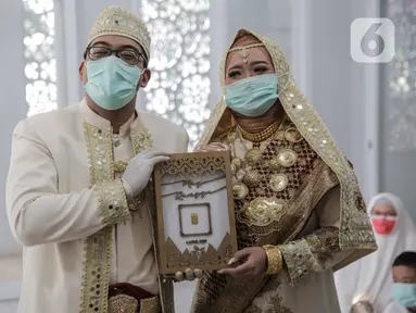 Sepasang pengantin seusai melaksanakan akad nikah di kawasan Pancoran, Jakarta, Rabu (1/4/2020). Pasangan tersebut menggelar pernikahan yang hanya dihadiri pihak keluarga mempelai guna menghindari pertemuan dengan orang banyak dan meminimalkan penyebaran COVID-19. (Liputan6.com/Faizal Fanani)