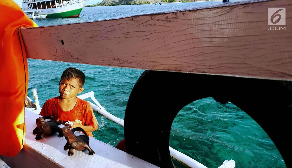 Kevin saat menawarkan kerajinan khas Pulau Komodo di atas kapal semi pinisi di Pink Beach, Taman Nasional Komodo, Sabtu, (9/10). Makanan kecil dan minuman di atas kapal dibawanya dari rumah. (Liputan6.com/Fery Pradolo)