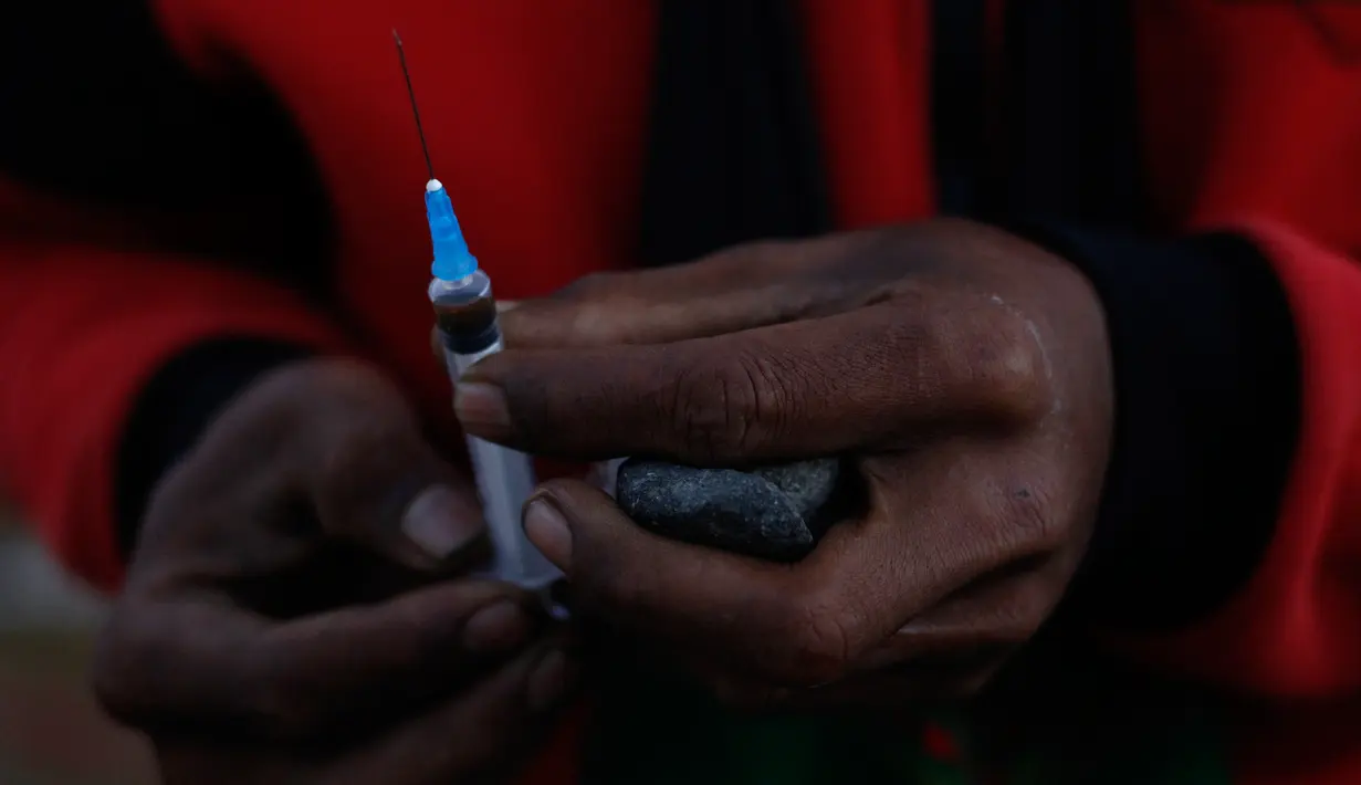 Seorang penambang bersiap menyuntikan jarum suntik berisikan heroin ke tubuhnya di Tambang batu giok di Hpakant, Myanmar, 29 November 2015. Kecanduan narkotika sudah merabak pada penambang batu giok. (REUTERS/Soe Zeya Tun)