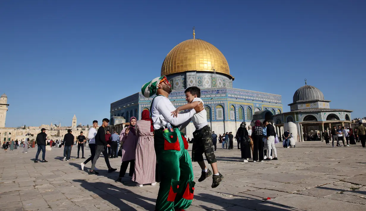 Umat Muslim merayakan setelah sholat Idul Fitri pagi, menandai akhir bulan suci Ramadhan, di luar masjid Kubah Batu di kompleks masjid Al-Aqsa di Yerusalem Tua (13/5/2021). (AFP/Ahmad Gharabli)