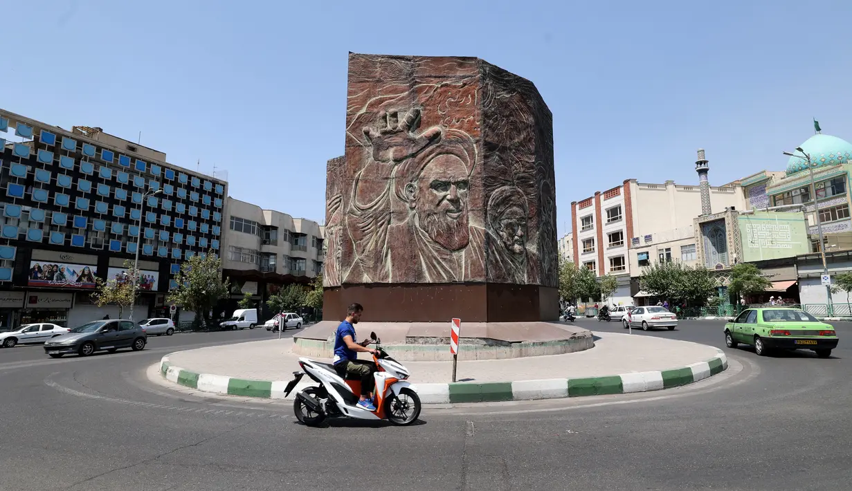 Pengendara motor melintasi di alun-alun Enghelab di pusat ibu kota Teheran ketika pihak berwenang memperketat pembatasan, Selasa (20/7/2021). Iran memberlakukan lockdown di Teheran dan provinsi terdekat setelah kasus infeksi Covid-19 mencapai rekor tertingginya selama wabah kelima. (ATTA KENARE/AFP)