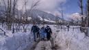 Tim petugas kesehatan dan dokter membawa vaksin saat mereka berjalan di jalan yang tertutup salju selama upaya vaksinasi COVID-19 di Budgam, barat daya Srinagar, Kashmir yang dikuasai India, pada 11 Januari 2022. (AP Photo/Dar Yasin)