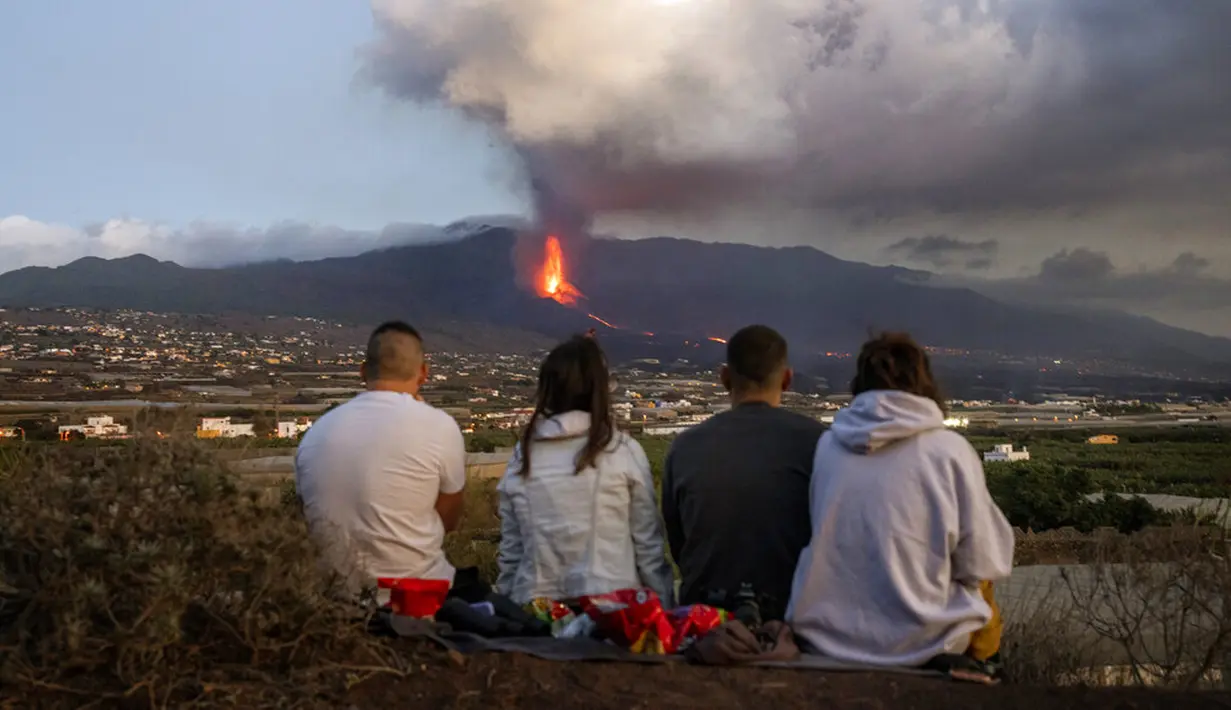 Warga menyaksikan lava mengalir dari gunung berapi yang meletus di Canary, Pulau La Palma, Spanyol, 26 Oktober 2021. Aliran lava baru telah muncul setelah runtuhnya sebagian kawah dan mengancam akan menelan daerah yang sebelumnya tidak terpengaruh. (AP Photo/Emilio Morenatti)