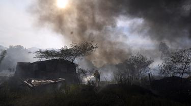 Petugas pemadam kebakaran menyiram gubuk untuk mencegahnya terbakar selama kebakaran semak di lingkungan Banco San Miguel di Asuncion, Paraguay (18/1/2022). Cuaca kering yang tidak biasa memicu kebakaran di lapangan terbuka, peternakan pribadi, dan lahan publik sekitar kota. (AP Photo/Jorge Saenz)