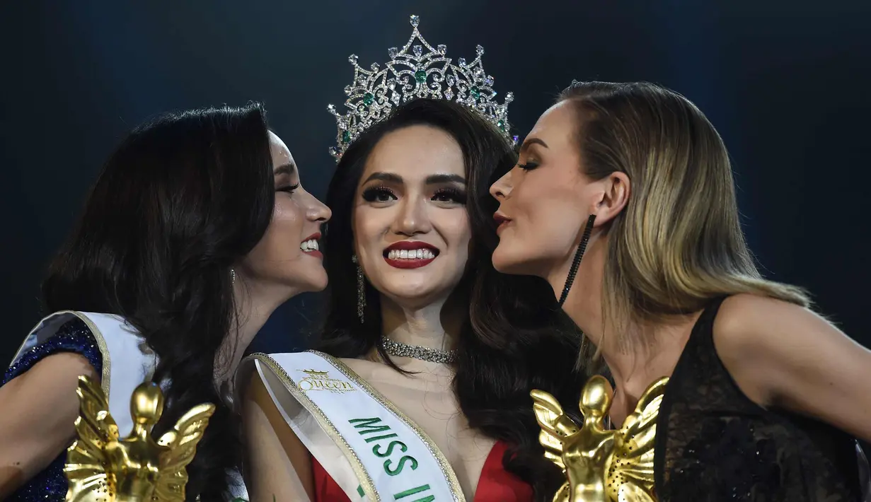 Nguyen Huong Giang dari Vietnam mendapatkan ciuman dari pesaingnya yang meraih juara dua, dan tiga dalam final kontes kecantikan transgender Miss International Queen 2018 di Pattaya, Thailand (9/3). (AFP Photo/Lillian Suwanrumpha)