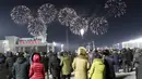 Pertunjukan kembang api menghiasi langit malam untuk merayakan Tahun Baru, saat kerumunan orang melihatnya, di Alun-alun Kim Il Sung di Pyongyang, Korea Utara, Jumat pagi, 1 Januari 2021. (AP Photo/Jon Chol Jin)