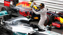 Pembalap Mercedes F1 Lewis Hamilton menyemprotkan sampanye ke mobilnya saat merayakan kemenangan Grand Prix di Monaco, (29/5). Ini merupakan kemenangan ke-44 sepanjang karier Hamilton. (REUTERS/Eric Gaillard)