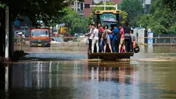 Sejumlah warga berada di ekskavator saat menuju kantor untuk bekerja di Wuhan, provinsi Hubei, (8/7). Curah hujan terberat yang mengguyur China selama beberapa hari terakhir telah mengakibatkan banjir merendam sejumlah daerah. (REUTERS/Stringer)