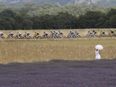 Seorang wanita dengan gaun dan payung putih menonton balapan Tour de France etape ke-19 dengan jarak tempuh 222,5 km dari Embrun menuju Salon-de-Provence, Prancis, (21/7/2017). (AP/Christophe Ena)
