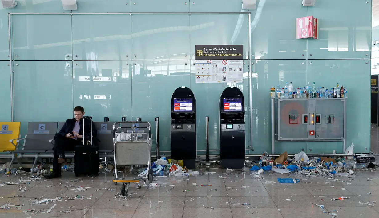 Seorang penumpang memainkan ponsel di antara sampah yang berserakan di Bandara Barcelona, Spanyol, Kamis (1/12). Para petugas kebersihan bandara tersebut menggelar aksi mogok kerja memprotes pengurangan anggaran sebesar 1,3 juta Euro. (REUTERS/Albert Gea)