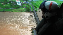 Anggota pasukan pertahanan India terlihat dari helikopter di lokasi jembatan utama yang runtuh akibat derasnya aliran sungai Savitri yang sedang meluap di barat India, Rabu (3/8). Dua bus yang membawa sedikitnya 22 penumpang terjun ke sungai itu. (AFP)