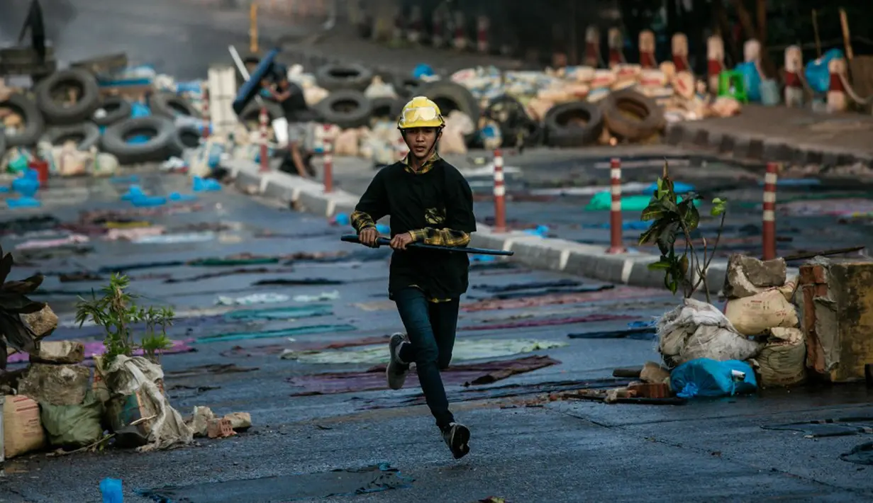 Seorang pengunjuk rasa yang membawa pedang berlari di sepanjang jalan selama tindakan keras oleh polisi terhadap demonstrasi menentang kudeta militer di Yangon, Myanmar, 16 Maret 2021. (STR/AFP)