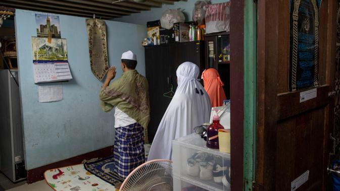 Keluarga Muslim Thailand melaksanakan salat setelah berbuka puasa di ruang tamu rumah mereka di Bangkok, pada 28 April 2020. Banyak tempat ibadah ditutup guna membendung penyebaran Virus Corona COVID-19 ketika Umat Muslim di seluruh dunia menyambut bulan suci Ramadan. (AP Photo/Gemunu Amarasinghe)