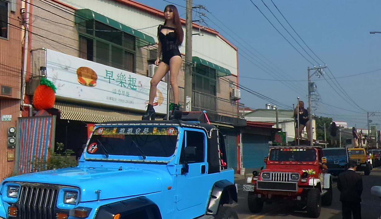Para penari striptis beraksi di atas sebuah jip selama upacara pemakaman seorang pejabat pemerintahan bernama Tung Hsiang di Kota Chiayi, Taiwan, (3/1). Sebanyak 50 penari striptis tersebut sengaja didatangkan oleh putra Tung Hsiang. (AFP PHOTO/STR)