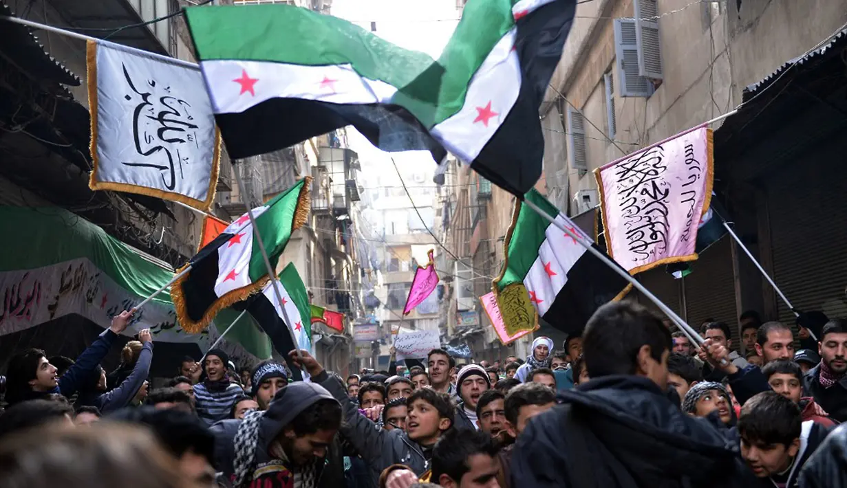 Pengunjuk rasa antirezim Suriah mengibarkan bendera Suriah pra-Baath, yang sekarang digunakan oleh Tentara Pembebasan Suriah, selama demonstrasi setelah salat Jumat di Distrik Bustan al-Qasr, Aleppo, Suriah, 8 Februari 2013. (Photo by AAMIR QURESHI/AFP)
